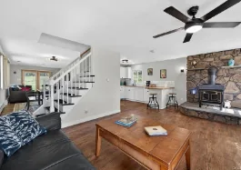 Before: the living room and kitchen with dated furnishings and a stone fireplace